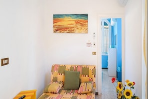 A room with a patterned sofa, a painting on the wall, and a door leading to another room.