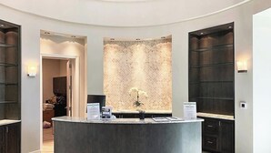 Un área de recepción con un mostrador central, un muro con diseño y armarios de madera oscura.