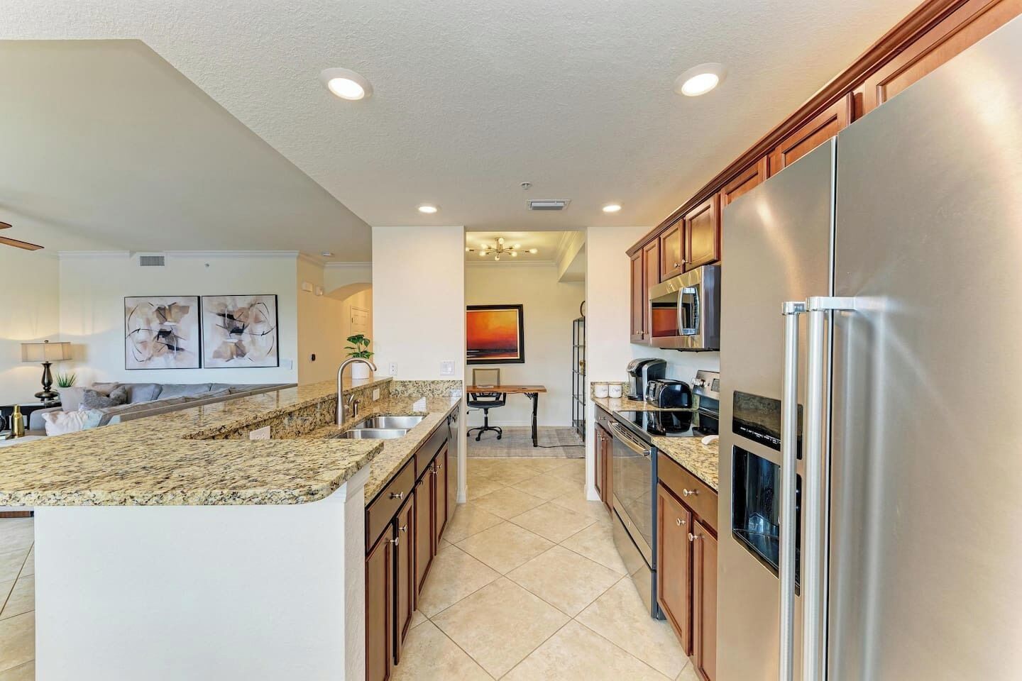 A modern kitchen with granite countertops, stainless steel appliances, and wooden cabinets.