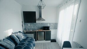 A compact living space with a bed, kitchenette, and a dining area.