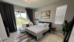 Ein Schlafzimmer mit einem großen Bett, einem Schlafsofa, einem kleinen Tisch und einer Pflanze.