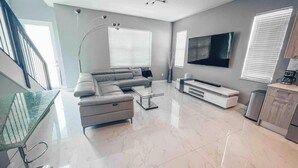 Ein modernes Wohnzimmer mit Sofa, Couchtisch und Fernseher.