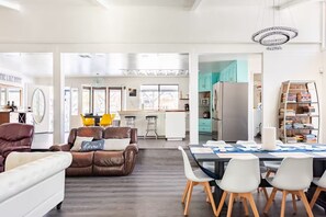 Un espacio habitable amplio con un sofá de cuero, una mesa de comedor con sillas y una cocina al fondo.