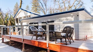 A cabin with a covered deck, outdoor seating, and a garage. - Yosemite Lakehouse Sleeps 20 + Hot Tub + Game Room + BBQ (Oakhurst)