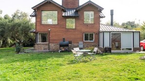 A two-story house with a brick exterior, a chimney, and a glass-enclosed porch.