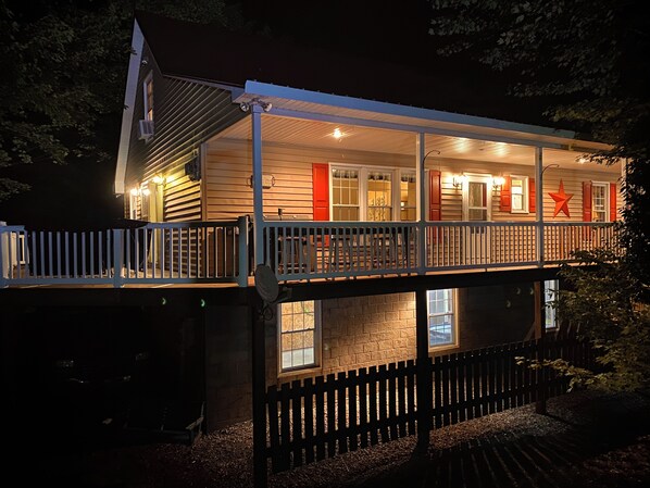 A two-story house with a balcony, a stone foundation, and a wooden fence. - Hidden Bliss-Large 4 bedroom home at Mt Storm Lake (Mount Storm)