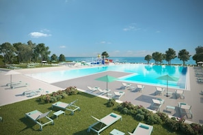 A swimming pool with lounge chairs and umbrellas, surrounded by trees and a clear sky.