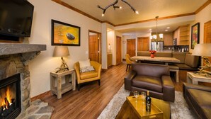 A cozy living room with a fireplace, leather sofas, a dining area, and a kitchen in the background.