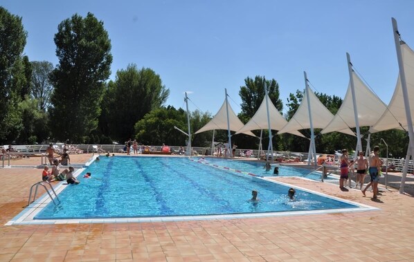 A swimming pool with multiple lanes, surrounded by shaded areas and a tiled deck.