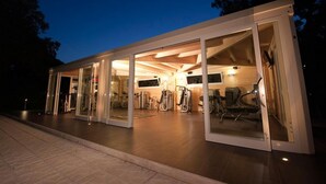 Une salle de sport moderne et bien éclairée, dotée de murs en verre et de divers appareils d’exercice.
