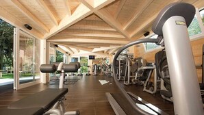 Une salle de sport avec des poutres en bois, du matériel d’exercice et de grandes fenêtres.