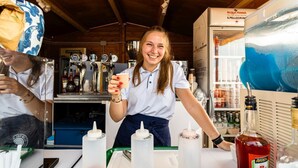 Zona de bar con mostrador, grifos de cerveza y nevera llena de bebidas.
