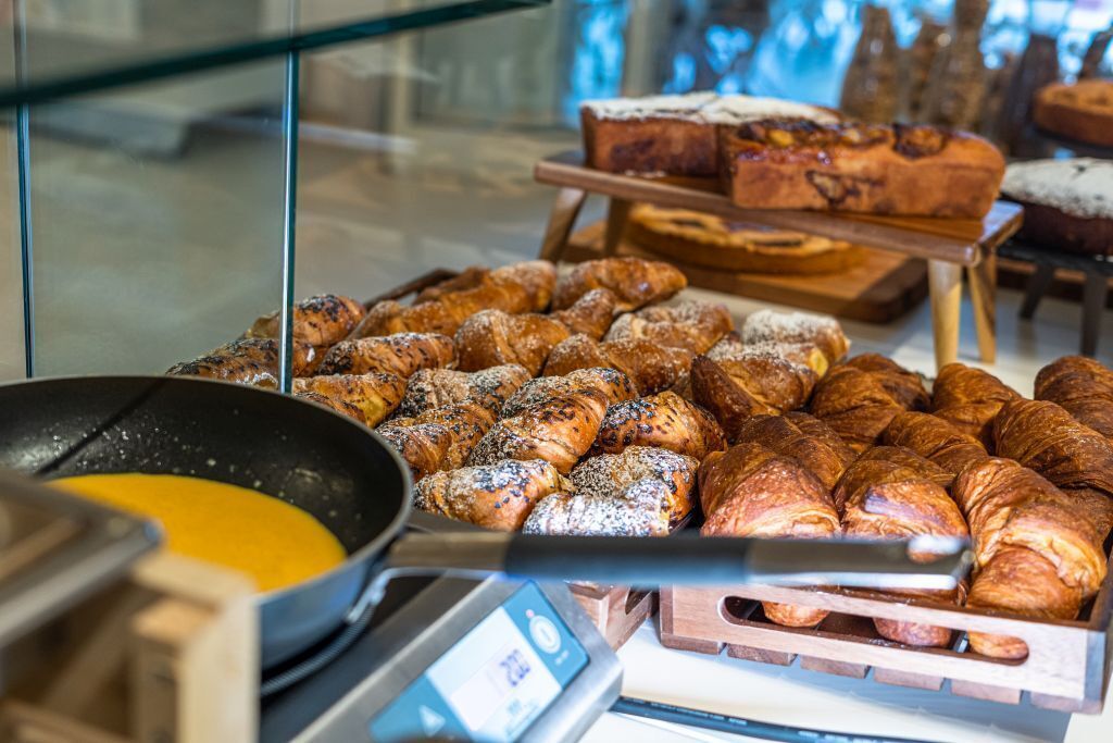 Eine Auswahl an Gebäck und Brot, darunter Croissants und Muffins, in einer Bäckerei.