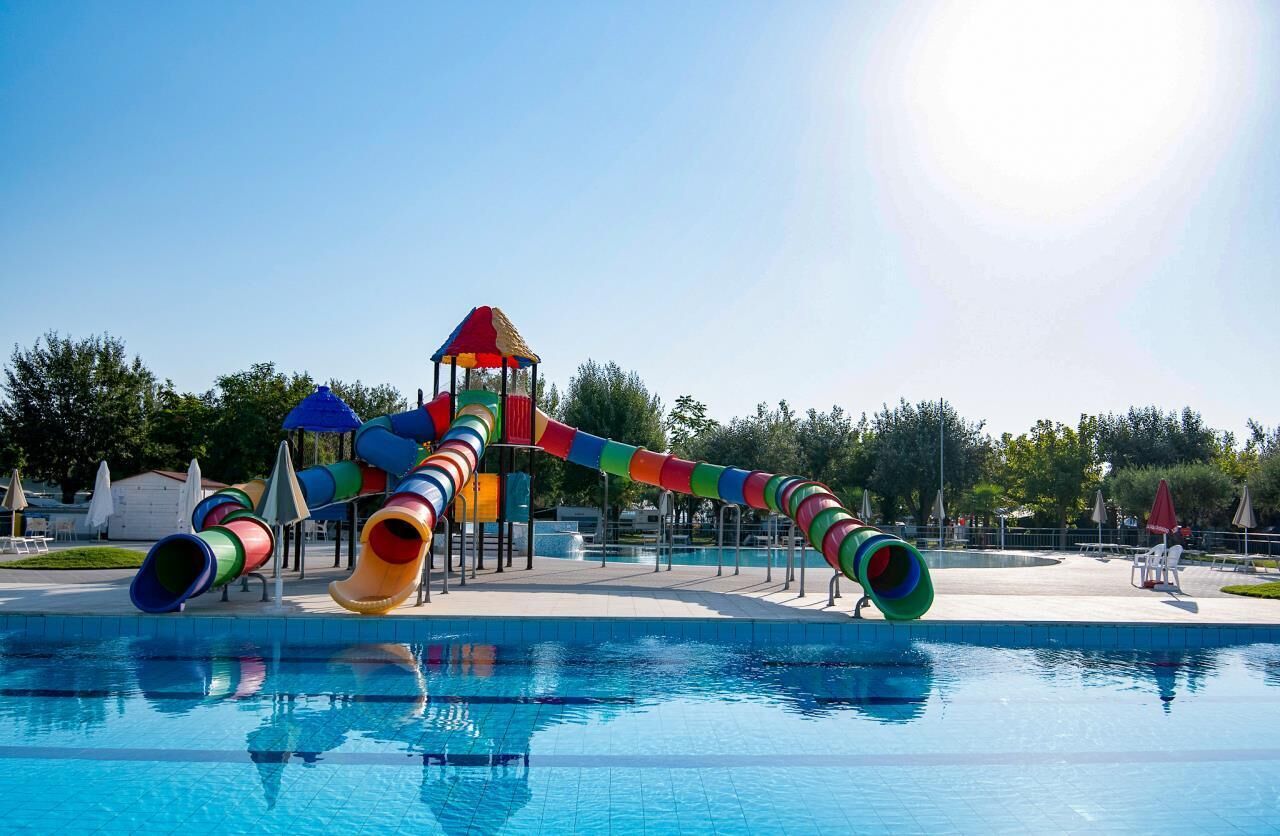 A swimming pool with a colorful water slide and play structure.