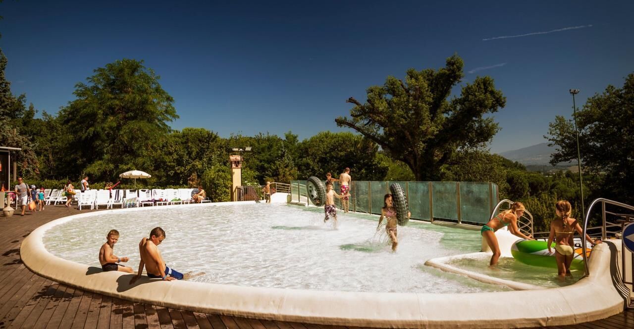 Un parco acquatico con piscina, scivoli e poltrone relax.
