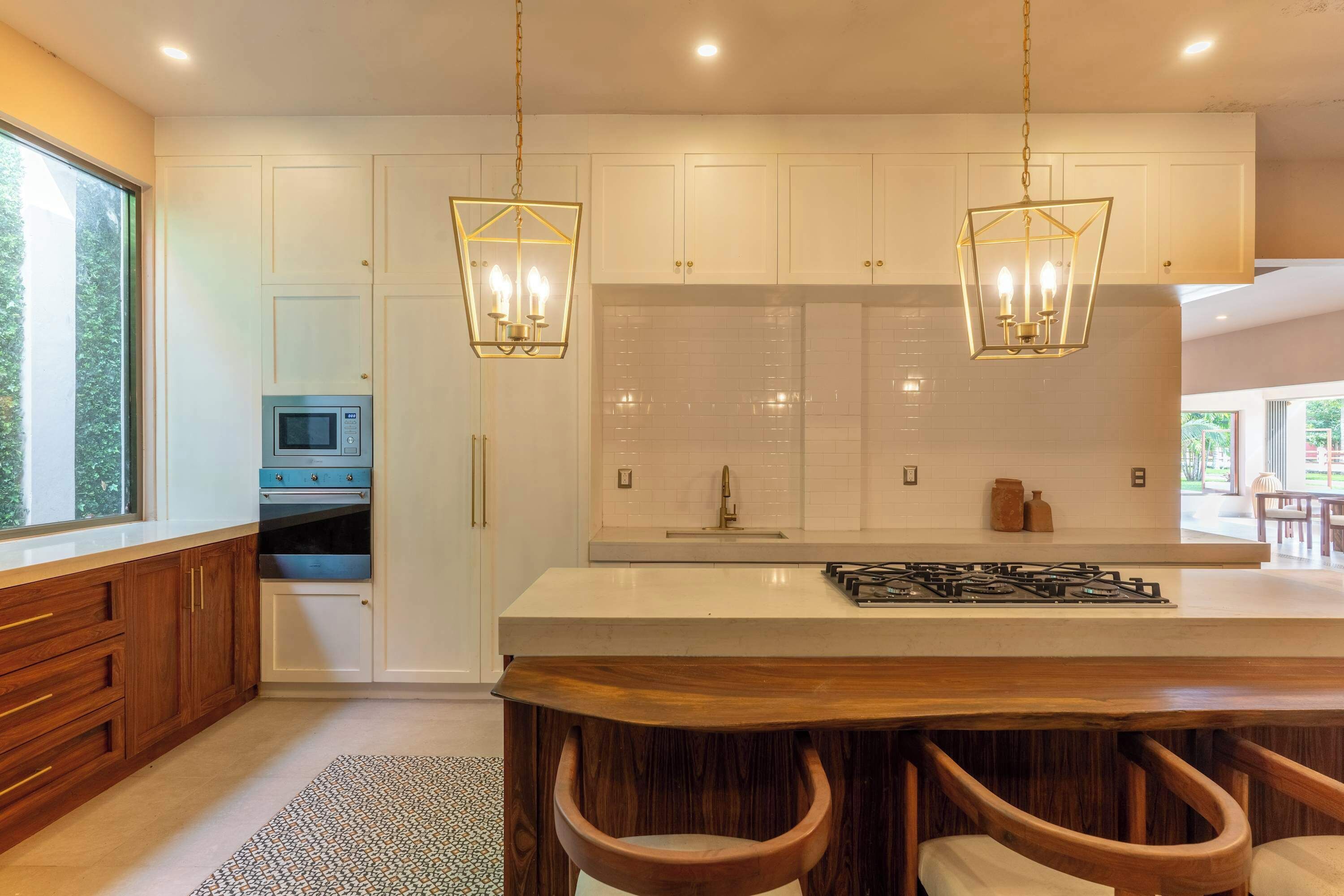A modern kitchen with white cabinets, a large island with stools, a microwave, and a gas stove.