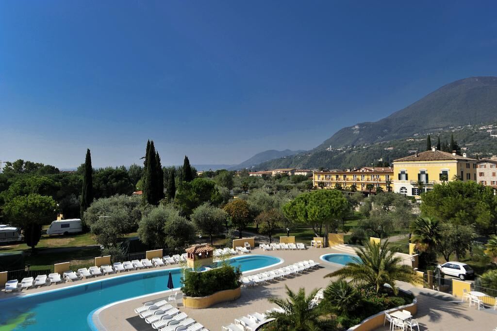 Un resort con una gran piscina, sillas de descanso y montañas al fondo.