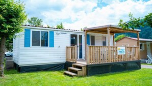 A mobile home with a wooden deck and a sign that reads "Happy Place."