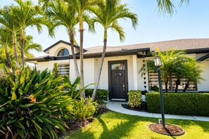 A modern house with a black door, surrounded by tropical plants and a well-maintained lawn. - Beautiful Home with Sauna & Heated Pool-Spa, 5min from Beaches, close to Airport (Lantana)