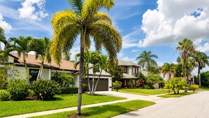 A residential street with houses, palm trees, and a clear sky. - Beautiful Home with Sauna & Heated Pool-Spa, 5min from Beaches, close to Airport (Lantana)