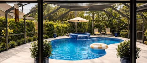 A swimming pool with a hot tub, surrounded by potted plants and a covered seating area.
