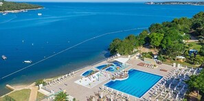 A resort with a large swimming pool, lounge chairs, and a view of the sea. - Valamar Camping Lanterna Mobilehome Happy Premium B for 7 persons (Tar)