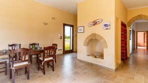 A dining area with a table and chairs, a stone fireplace, and a door leading outside. - Holiday Home 'Casa Del Sol' with Private Terrace, Wi-Fi and Air Conditioning (Andrano)