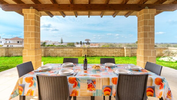 An outdoor dining area with a table set for four, a bottle of wine, and a view of the landscape. - Holiday Home 'Casa Del Sol' with Private Terrace, Wi-Fi and Air Conditioning (Andrano)