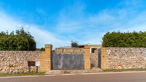 A gated entrance with a stone wall, a metal gate with musical notes, and a clear sky. - Holiday Home 'Casa Del Sol' with Private Terrace, Wi-Fi and Air Conditioning (Andrano)
