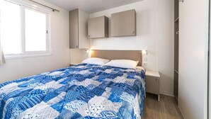 Un dormitorio con cama, mesita de noche, armario y ventana.