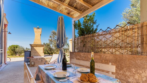 An outdoor dining area with a table set for two, a bottle of wine, and cookies.