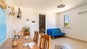 A dining area with a wooden table, chairs, a vase, and a blue sofa.