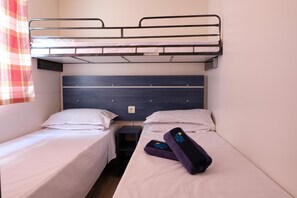 Cozy accommodations feature a bunk bed and a single bed with a bedside table and lamp.
