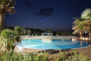 Relax by the pool surrounded by lush greenery and a shaded gazebo.
