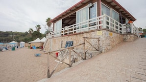 A beachside building with a stone facade, a wooden staircase, and a balcony with a railing. - Ferienanlage Manacore Mobilehome Happy Easy für 6 Personen (Manaccora)