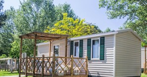 Situated in a wooded area, this mobile home offers a cozy outdoor seating area on its covered porch.