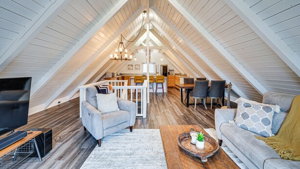 A spacious attic bedroom with a loft-style kitchen, a large window, and a modern chandelier. - Stylish Bellingham Home w/ Lake + Mountain Views! (Bellingham)