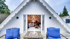 A cozy attic bedroom with a fireplace, two blue cushioned chairs, and a view of the living area. - Stylish Bellingham Home w/ Lake + Mountain Views! (Bellingham)