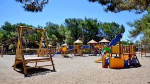 Un parque infantil con diversas estructuras de juego, incluyendo toboganes y zonas de escalada, rodeado de árboles.