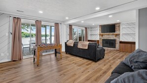 Ein modernes Wohnzimmer mit Kicker, einer Couch, einem Kamin und einem Fernseher.