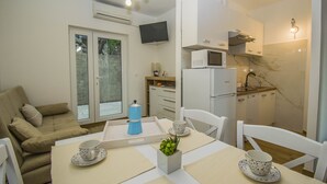 Un espacio habitable compacto con comedor, kitchenette y sofá.