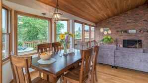 A dining area with a wooden table, chairs, and a vase of flowers. There is a brick wall and a fireplace in the background. - Tabor Hillside Retreat over the trees, walk to trails, and Montavilla cafes.  (Portland)