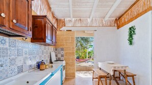 A kitchen with a tiled backsplash, wooden cabinets, a stove, and a dining area with benches.