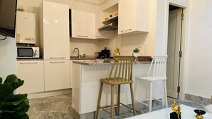 Cozinha moderna com armários brancos, micro-ondas embutido e bancada de granito.