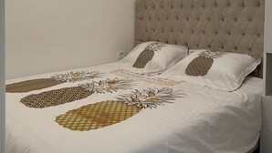 Quarto com uma cama, cabeceira estofada e luminária sobre a cama.