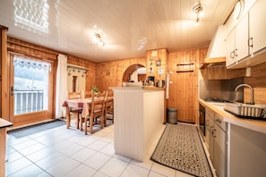 A wooden interior with a kitchen, dining area, and a view through a door.