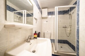 Une salle de bain équipée d’un lavabo, d’un miroir, d’une douche et de toilettes.