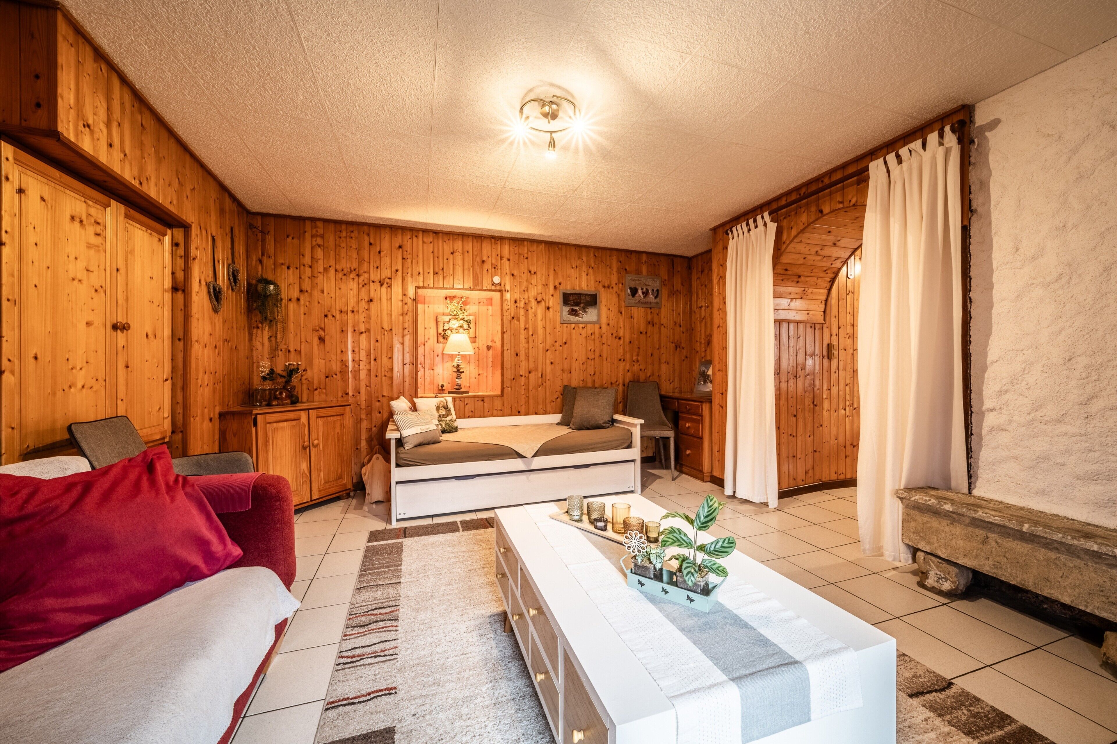 A wooden interior with a sofa, a bench, a coffee table, and a lamp.