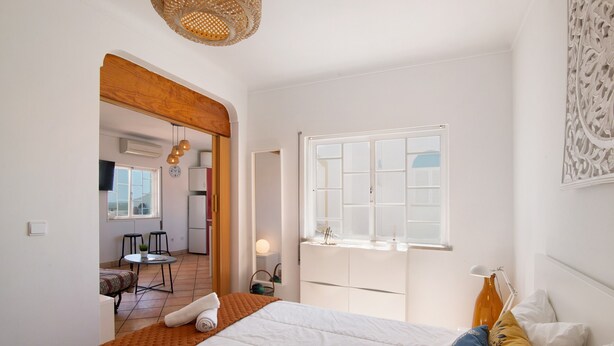 Une chambre à coucher comprenant un lit, une fenêtre, une porte et donnant sur un coin repas.