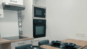 Een moderne keuken met een eettafel gedekt voor vier personen, met zwarte borden en bestek, en een magnetron boven de oven.